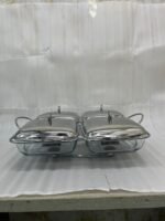 A luxurious Paramount Series 5-in-1 food warmer set on a wooden dining table, featuring four 2.5L glass serving dishes with polished stainless steel lids and tealight buffet burners underneath.