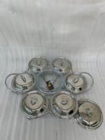 Paramount Series 7-in-1 buffet food warmer set featuring seven clear glass bowls with polished stainless steel lids and a silver metal stand with buffet burners on a decorated dining table.