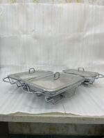 Three elegant Paramount Series food warmers in different sizes (1.5L, 2.4L, and 3L) featuring stainless steel lids and glass dishes with candle-lit buffet burners on a dining table.