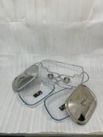 A Paramount Series double stainless steel food warmer on a dining table, featuring two 1.5L glass dishes with lids being lifted to reveal steaming food, supported by a chrome frame with two lit buffet burners underneath.