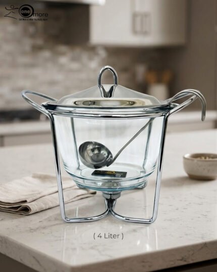 A 4-liter Paramount Series food warmer featuring a clear glass bowl, stainless steel stand, and lid, shown on a dining table with guests and filled with warm lentil soup.