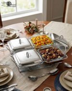 A luxurious Paramount Series 5-in-1 food warmer set on a wooden dining table, featuring four 2.5L glass serving dishes with polished stainless steel lids and tealight buffet burners underneath.