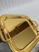 Three-piece set of luxury gold-plated stainless steel serving trays with intricate floral engravings and textured handles, displayed on a formal dining table.