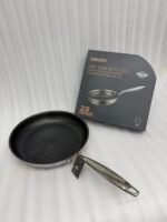 A set of three UAKEEN premium tri-ply stainless steel fry pans with laser-etched honeycomb non-stick interiors, shown in 24cm, 26cm, and 28cm sizes on a marble countertop with an induction-compatible base.