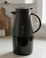 Three 2-liter luxury stainless steel thermal flasks in black, cream, and grey finishes with metallic handles, arranged on a white marble kitchen counter.