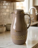 A trio of elegant 2-liter Feenik thermal flasks in cream, grey, and taupe featuring gold floral patterns on a marble kitchen countertop.