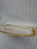 A set of three nesting stainless steel rectangular serving trays with gold rope borders, floral engravings, and ornate gold handles, displayed on a dark wooden dining table with elegant dinnerware.