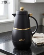 Three DayDays 1-liter luxury thermal flasks in white, black, and purple with gold accents displayed on a granite kitchen countertop.