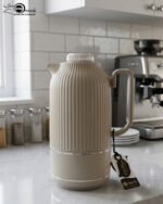 A collection of three 1-liter Feenik thermal flasks featuring a vertical ribbed design in beige, gray, and taupe on a white marble countertop.