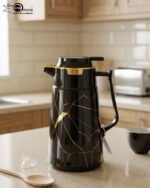 Three elegant 1-liter vacuum flasks in black, grey, and cream colors, featuring a golden Kintsugi-inspired marble pattern on a kitchen countertop.