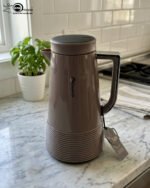 A trio of Feenik 1-liter thermal vacuum flasks in cream, sand grey, and mocha colors, displayed on a marble kitchen countertop.