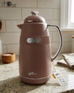 Three 1-liter DayDays thermal flasks in Dusty Rose, Warm Sand, and Stone Grey arranged on a granite kitchen countertop.