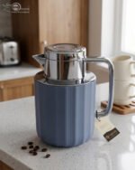 Three 1-liter Nordic-style thermal flasks in Slate Blue, Sand Beige, and Soft Rose colors with fluted textures and metallic lids displayed on a kitchen counter.