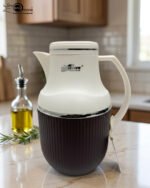 Three 1-liter modern vacuum flasks with cream-colored tops and ribbed bases in brown, grey, and beige, displayed on a white marble kitchen countertop.