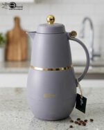 Three DayDays 1-liter luxury thermal flasks in white, black, and purple with gold accents displayed on a granite kitchen countertop.