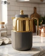 Three luxury 1-liter thermal flasks in white, grey, and black with polished gold tops and ribbed textured bases on a marble kitchen counter.