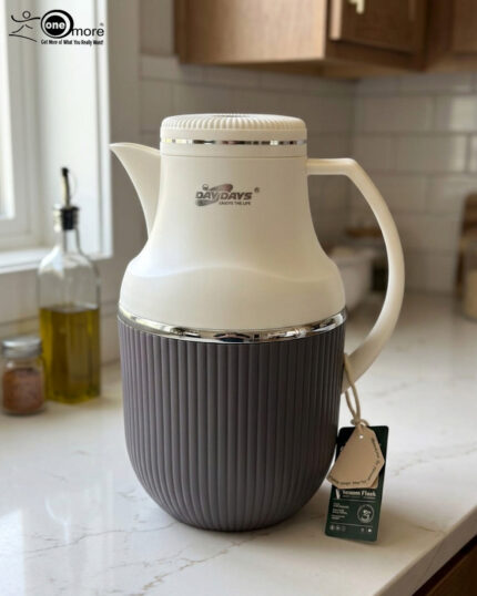 Three 1-liter modern vacuum flasks with cream-colored tops and ribbed bases in brown, grey, and beige, displayed on a white marble kitchen countertop.