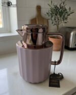 Three 1-liter Nordic-style thermal flasks in Slate Blue, Sand Beige, and Soft Rose colors with fluted textures and metallic lids displayed on a kitchen counter.