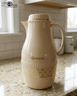 A trio of elegant 2-liter Feenik thermal flasks in cream, grey, and taupe featuring gold floral patterns on a marble kitchen countertop.