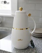 Three DayDays 1-liter luxury thermal flasks in white, black, and purple with gold accents displayed on a granite kitchen countertop.