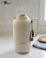 A collection of three 1-liter Feenik thermal flasks featuring a vertical ribbed design in beige, gray, and taupe on a white marble countertop.
