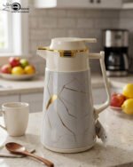 Three elegant 1-liter vacuum flasks in black, grey, and cream colors, featuring a golden Kintsugi-inspired marble pattern on a kitchen countertop.