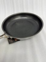 A set of three UAKEEN premium tri-ply stainless steel fry pans with laser-etched honeycomb non-stick interiors, shown in 24cm, 26cm, and 28cm sizes on a marble countertop with an induction-compatible base.