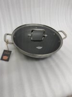 High-angle shot of two Uakeen stainless steel non-stick woks in 30cm and 32cm sizes on a wooden countertop, showing the laser-etched hexagonal interior and tempered glass lids.