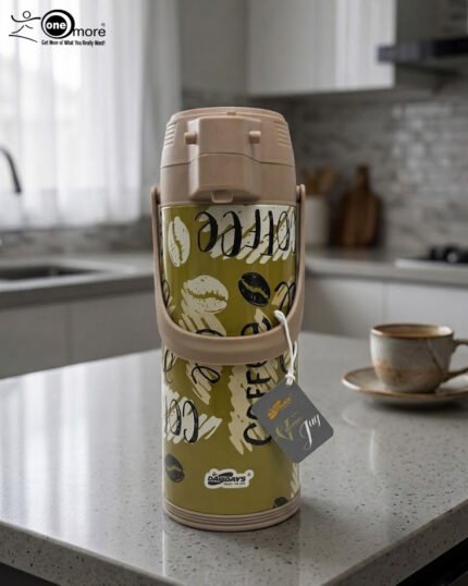 A 1.9-liter olive green Day Days vacuum insulated coffee airpot with a brown pump-action lid and handle, featuring a decorative coffee bean pattern, displayed on a kitchen counter next to a coffee cup.