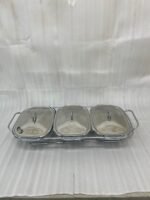 A Paramount Series 3-in-1 buffet food warmer featuring three square glass serving dishes with stainless steel lids on a chrome wire rack, displayed on a kitchen counter and an outdoor dining table with tea light candles lit underneath.