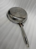 A set of three UAKEEN premium tri-ply stainless steel fry pans with laser-etched honeycomb non-stick interiors, shown in 24cm, 26cm, and 28cm sizes on a marble countertop with an induction-compatible base.