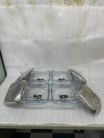 A luxurious Paramount Series 5-in-1 food warmer set on a wooden dining table, featuring four 2.5L glass serving dishes with polished stainless steel lids and tealight buffet burners underneath.