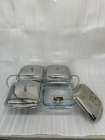 A luxurious Paramount Series 5-in-1 food warmer set on a wooden dining table, featuring four 2.5L glass serving dishes with polished stainless steel lids and tealight buffet burners underneath.