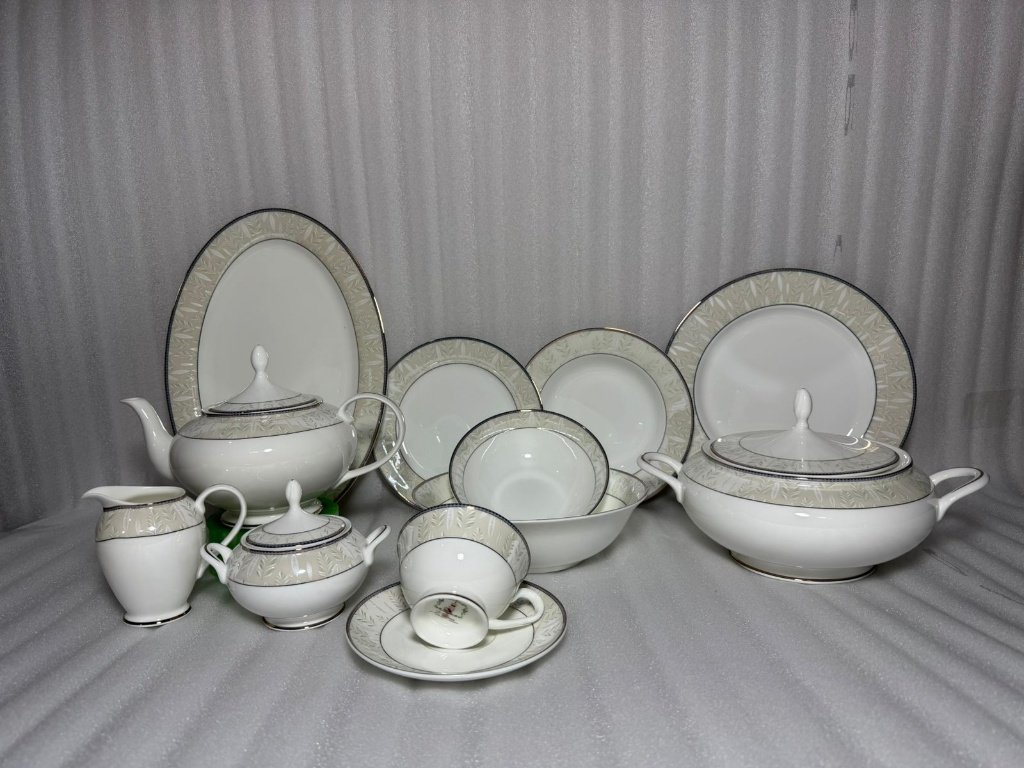 a16ec0d9-9384-4c68-9893-23c6074ff7db A comprehensive 61-piece Super Bone China dinner set featuring a white finish with a beige leaf pattern border and silver rims, arranged against a neutral background.