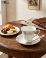 A complete Super Bone China dinner set from 6.jpg, featuring a white base with intricate grey floral borders. The set includes plates, bowls, a teapot, a tureen, and teacups displayed on a wooden surface