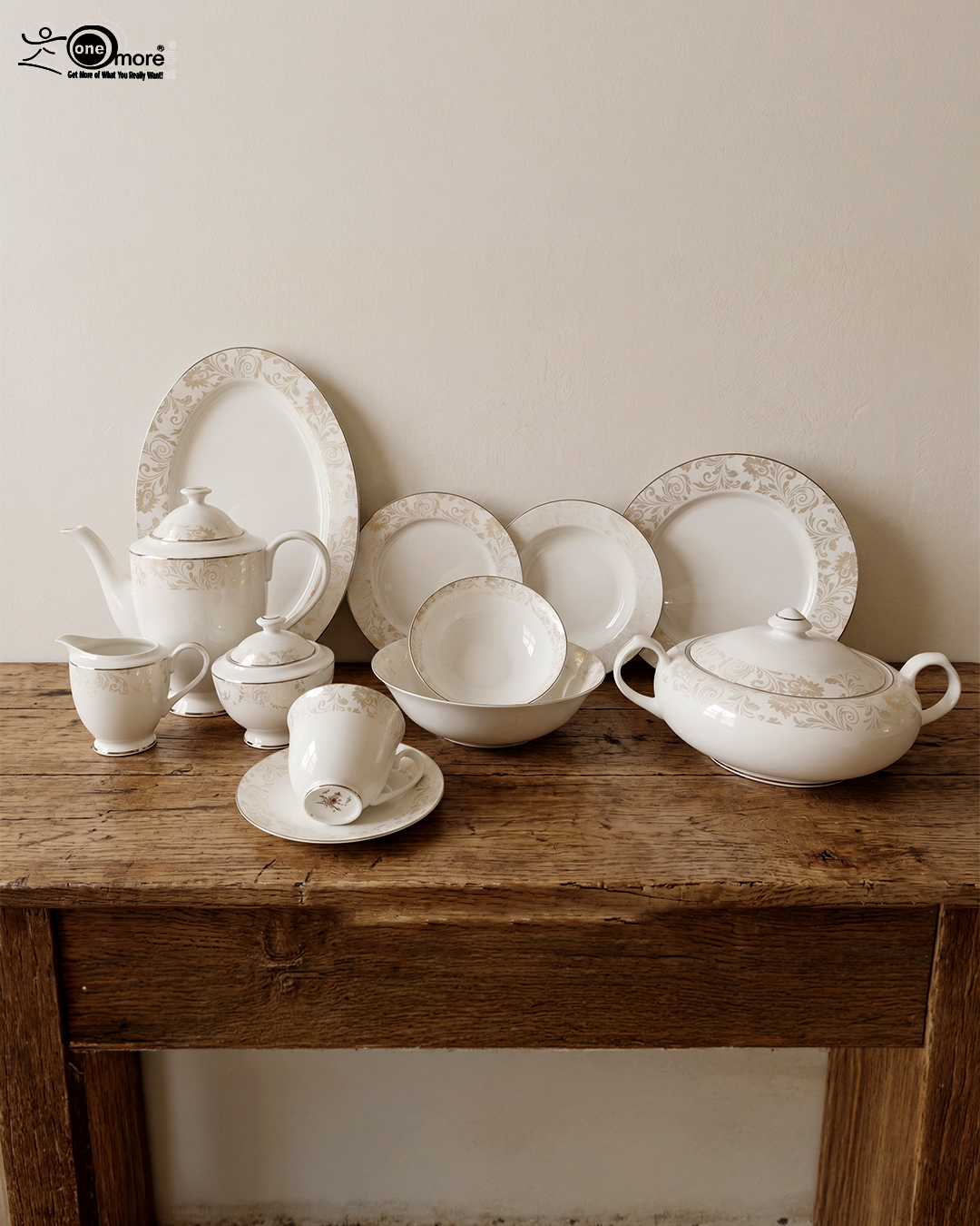 1 A comprehensive 61-piece super bone china dinner set arranged for display against a neutral textured background. The white porcelain tableware features a delicate cream and gold floral pattern on the rims. The collection includes dinner plates, side plates, soup bowls, a large oval platter, a lidded serving tureen, a teapot with matching sugar bowl and creamer, and teacups with saucers