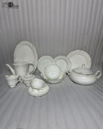 Detailed product photograph of an elegant 61-piece super bone china dinner set for 8-person serving, displayed on a polished wooden surface. The set includes a full tea service (teapot, creamer, sugar bowl, teacup and saucer), multiple plates and bowls, a large lidded tureen, and various serving pieces, all featuring delicate light gold damask filigree patterns and gold trim on a cream-white surface. The 'one more' brand logo is visible in the upper left corner.