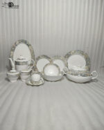 An elegant 61-piece premium super bone china dinner set with grey and gold marbled rims displayed on a warm wooden tabletop, featuring luxury plates, bowls, a covered tureen, and a teapot setup