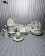 A premium 61-piece white super bone china dinner set with a delicate green and gold floral pattern displayed on a polished dark wood table. The set features an elegant teapot, casserole tureen, serving bowls, large oval platter, dinner plates, side plates, and tea cups with saucers against a neutral textured background