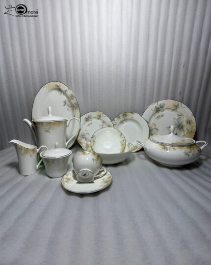 A premium 61-piece white super bone china dinner set with a delicate green and gold floral pattern displayed on a polished dark wood table. The set features an elegant teapot, casserole tureen, serving bowls, large oval platter, dinner plates, side plates, and tea cups with saucers against a neutral textured background