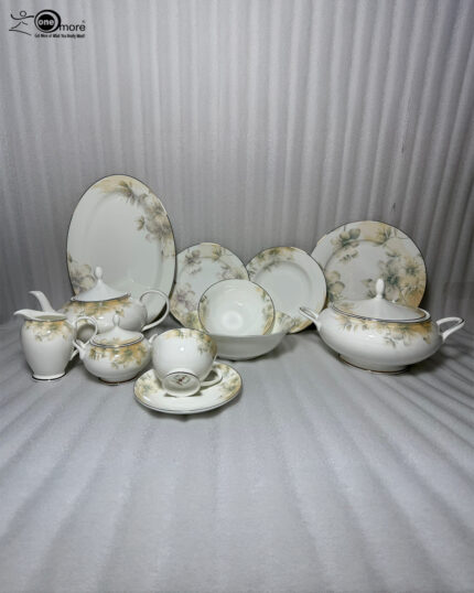 An elegant 61-piece One More brand super bone china dinnerware set with gold rims and soft floral patterns, arranged beautifully on a wooden table with a white runner