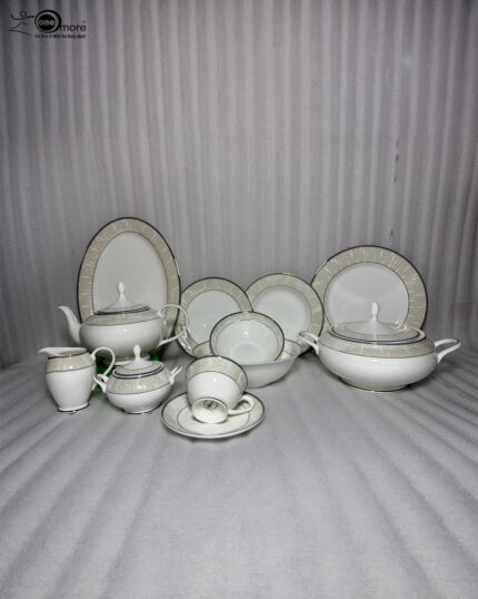 An elegant 61-piece super bone china dinnerware set for an 8-person serving, featuring white plates, bowls, a teapot, a covered tureen, and teacups with detailed beige and silver patterned rims, neatly arranged on a wooden table