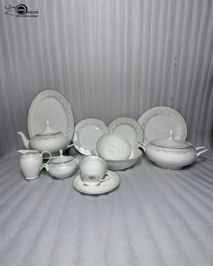 Elegant 61-piece super bone china dinner set by OneMore with an intricate silver lace border design, beautifully arranged on a wooden table against a plain background, including plates, bowls, a teapot, and a soup tureen