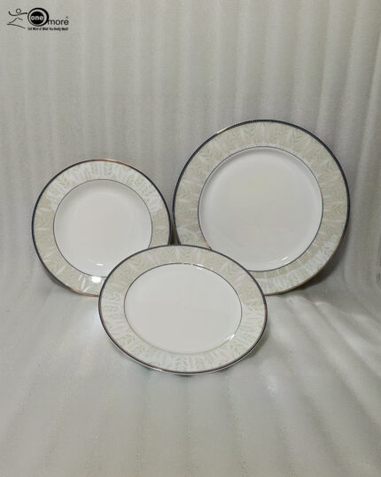 A professionally styled stack of the OneMore 18-piece super bone china dinnerware set, showcasing six quarter plates on top, six deep plates in the middle, and six large rice plates at the bottom, featuring an elegant light-green patterned border on a silver table runner