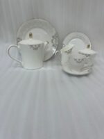 A complete 24-piece porcelain tea set featuring a teapot, sugar bowl, milk jug, tea cups, saucers, and plates, all decorated with intricate grey filigree patterns and gold accents, displayed on a marble surface.