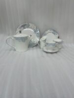 A complete 24-piece luxury porcelain tea set featuring a delicate blue floral pattern on white china with silver rims, displayed on a wooden table.
