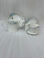 A 24-piece luxury porcelain tea set featuring a white base, marble-patterned rims in blue and grey, and delicate gold detailing, arranged on a wooden table.