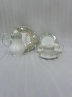 A 24-piece luxury porcelain tea set featuring white dishes with soft green, brush-stroke patterned edges and delicate gold rims, displayed on a wooden surface.