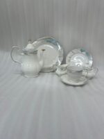 A luxurious 24-piece porcelain tea set featuring white ceramic with blue marble patterns and gold trim, displayed on a marble surface.