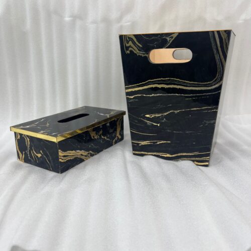 Luxury black and gold marble pattern dustbin and matching tissue box holder on a wooden vanity next to a marble bathroom sink.